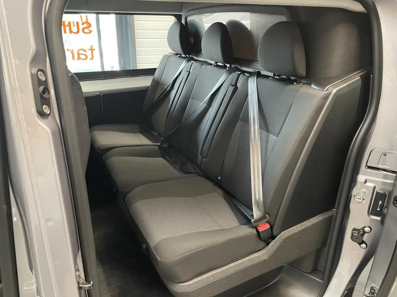 Vue intérieure de la banquette arrière trois places en tissu gris du Peugeot Expert Fourgon gris Artense, côté droit ouvert.