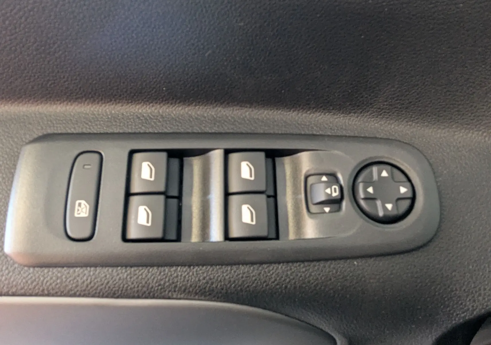 Vue rapprochée des commandes de lève-vitres et réglage des rétroviseurs sur porte intérieure noire du Citroën Berlingo gris Artense 2026.
