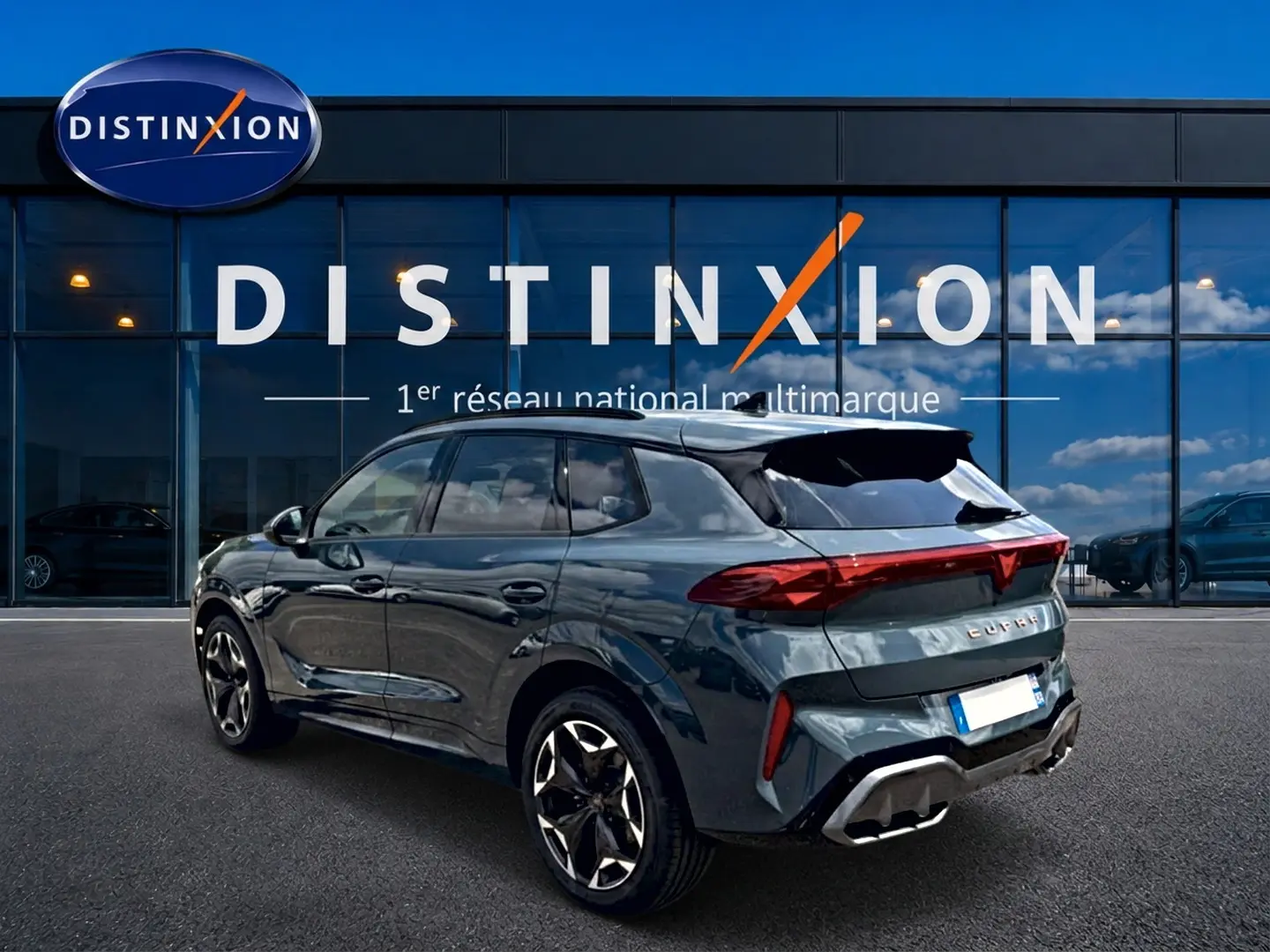 Vue 3/4 arrière droite d'un CUPRA Terramar bleu fjord avec jantes 19 pouces devant une vitrine Distinxion.