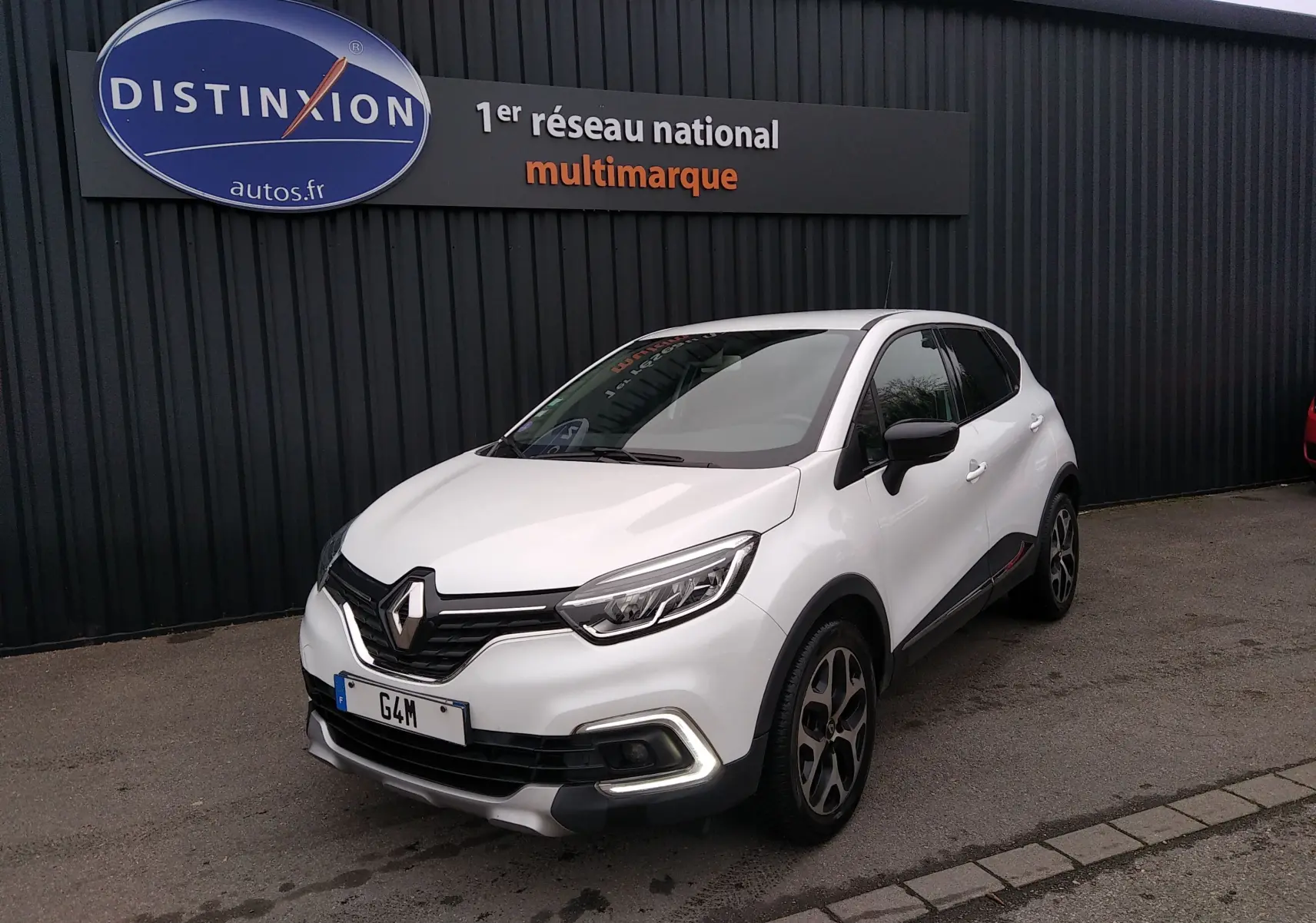 Renault Captur blanc en 3/4 avant droit, avec signature lumineuse LED et jantes alliage noires et argentées.