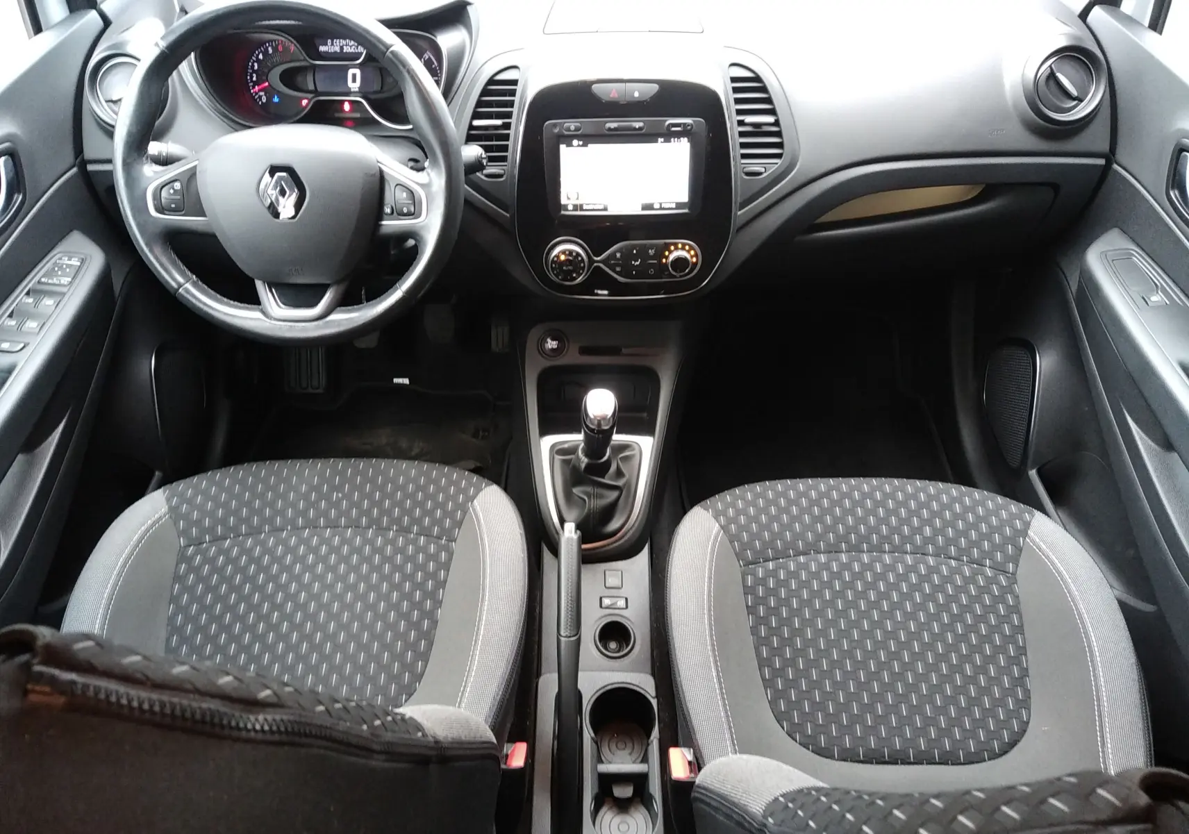 Vue intérieure avant du Renault Captur blanc 2017, volant multifonction, tableau de bord avec écran tactile et boîte manuelle.