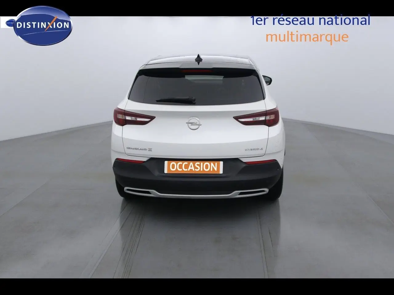 Vue arrière d'un Opel Grandland X blanc nacré hybride rechargeable, avec feux arrière LED et plaque occasion visible.