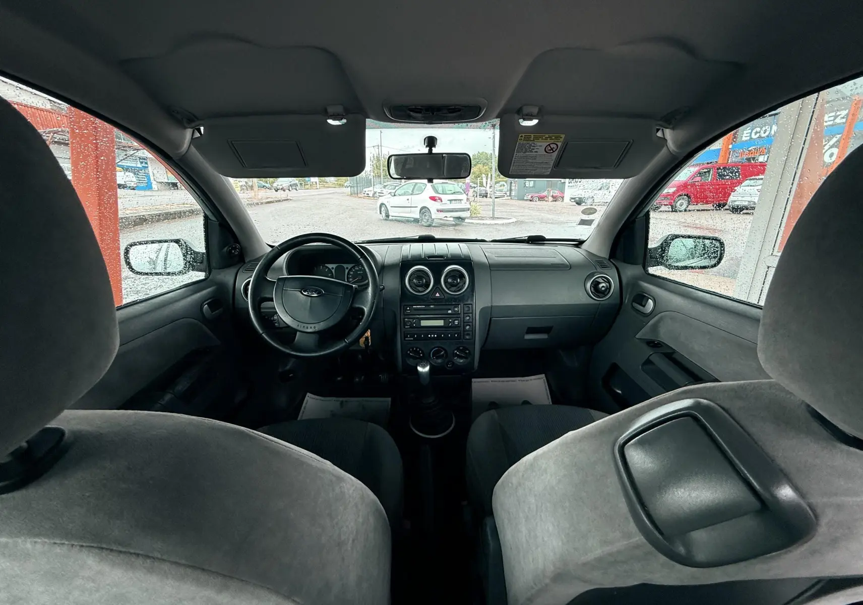 Vue intérieure avant de la Ford Fusion 2002 avec tableau de bord noir et sièges tissu gris clair.