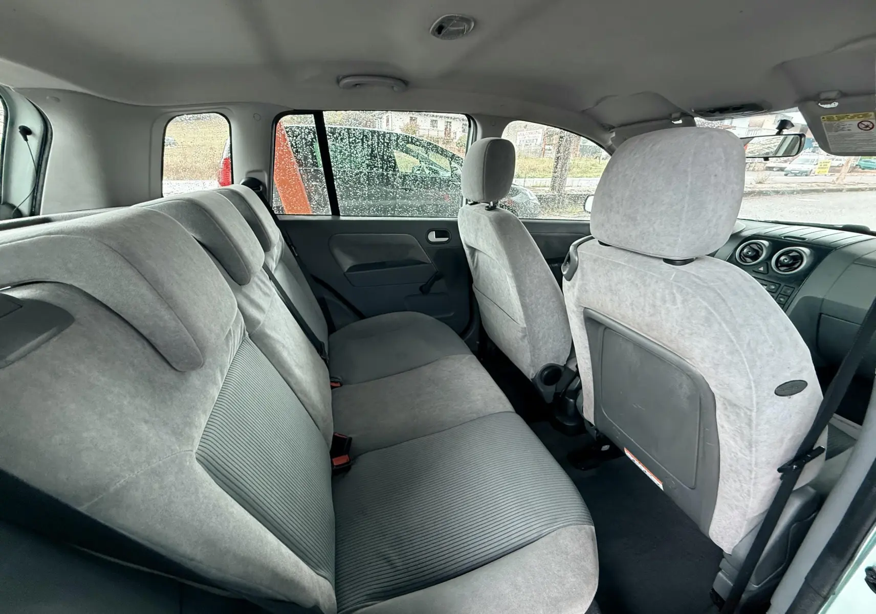 Vue intérieure arrière montrant les sièges gris clair de la Ford Fusion 2002 avec une porte arrière ouverte côté droit.