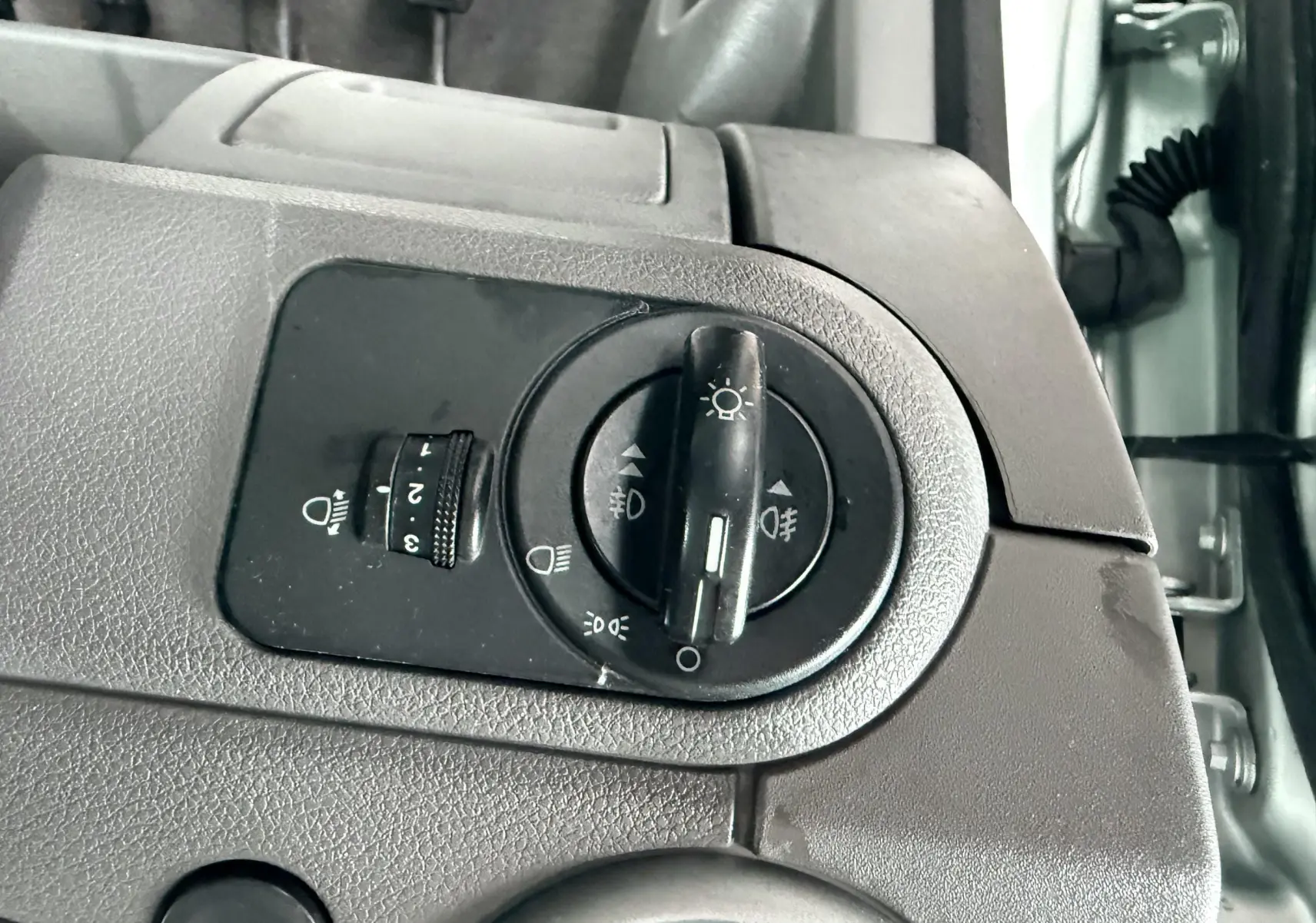 Gros plan sur le bouton de commande des phares de la Ford Fusion 2002 bleu clair, côté intérieur conducteur.