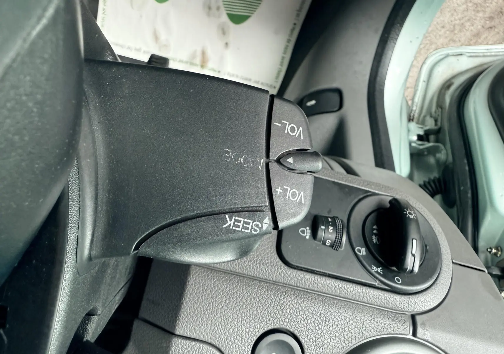 Gros plan sur les commandes de volume et phares à gauche du volant d'une Ford Fusion bleu clair de 2002.