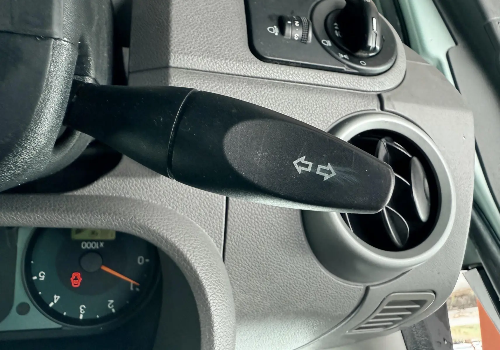 Gros plan sur le commodo de clignotant noir et la console grise à côté du volant d'une Ford Fusion bleu clair de 2002.