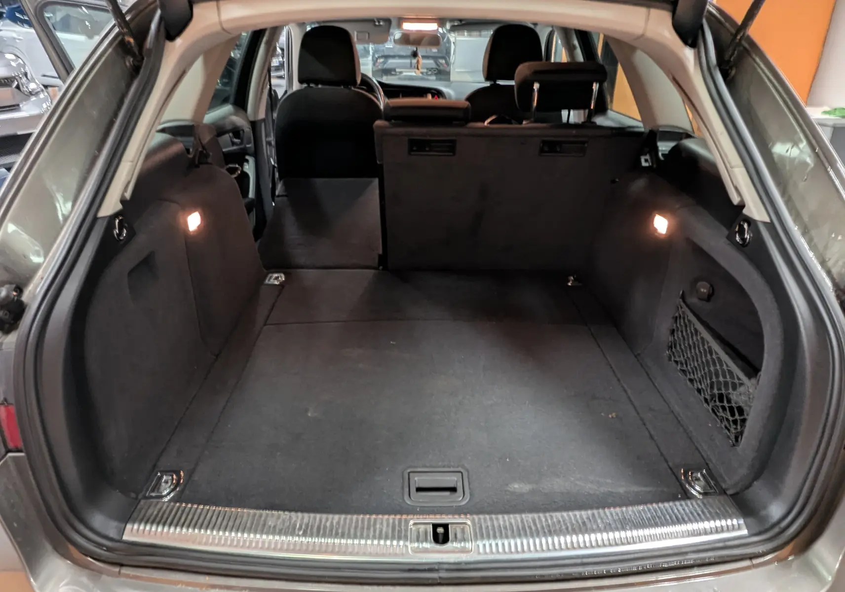 Coffre ouvert d'une Audi A4 gris 2013, vue arrière montrant l'espace de chargement et les sièges rabattus.