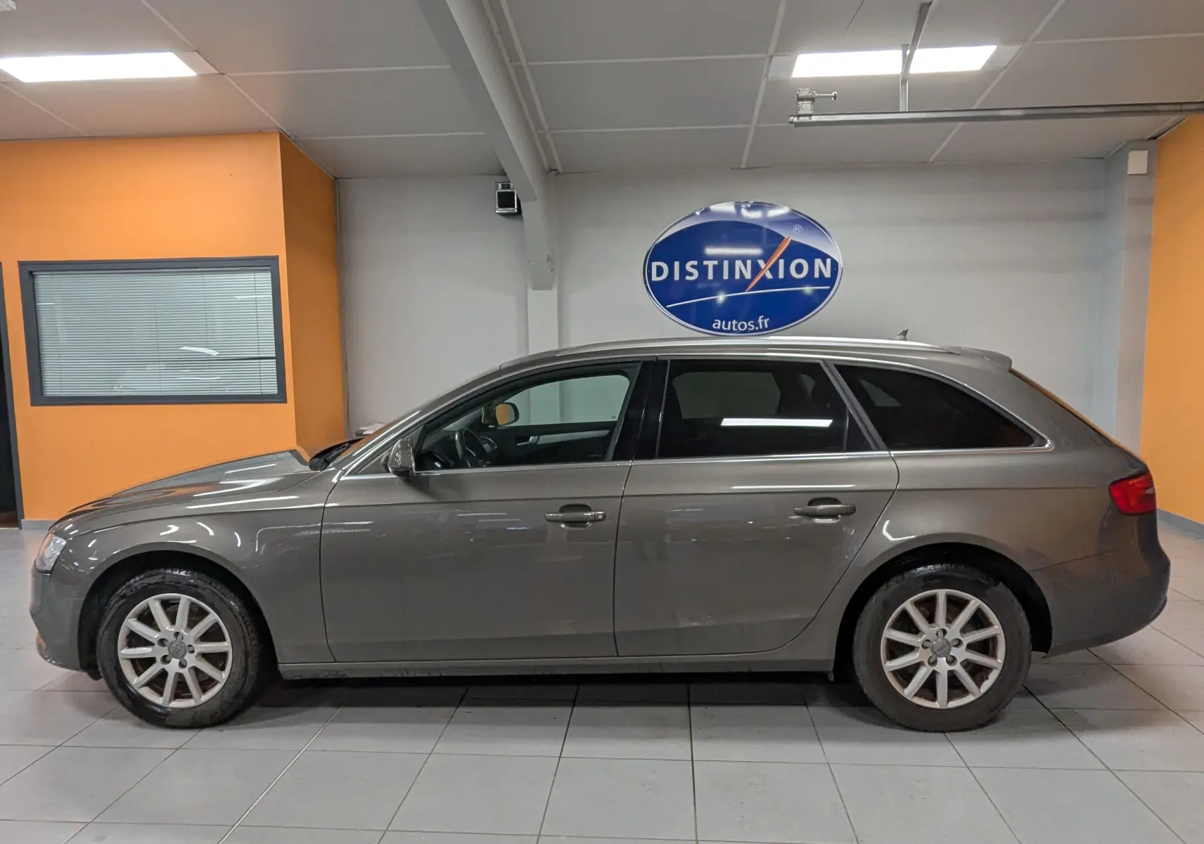 Profil côté gauche d'une Audi A4 break gris 2013 en intérieur, avec jantes alliage et vitres teintées.