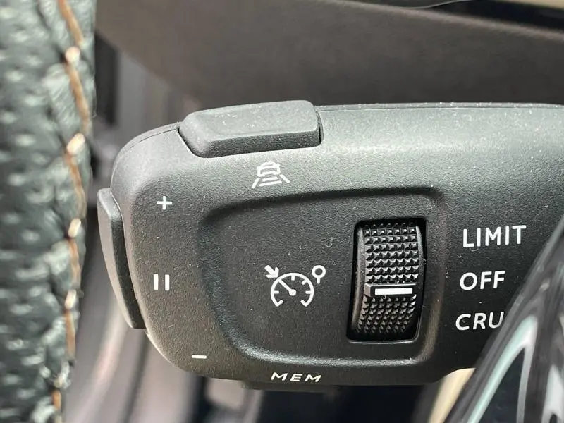 Gros plan sur la commande de régulateur de vitesse au volant cuir d'une Peugeot 508 SW gris Selenium.