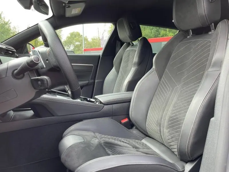 Vue intérieure côté gauche des sièges avant en cuir et Alcantara gris foncé du Peugeot 508 SW 2024, avec volant multifonction.