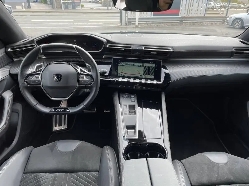 Vue intérieure avant du Peugeot 508 SW 2024, tableau de bord noir avec écran tactile et volant GT compact cuir.