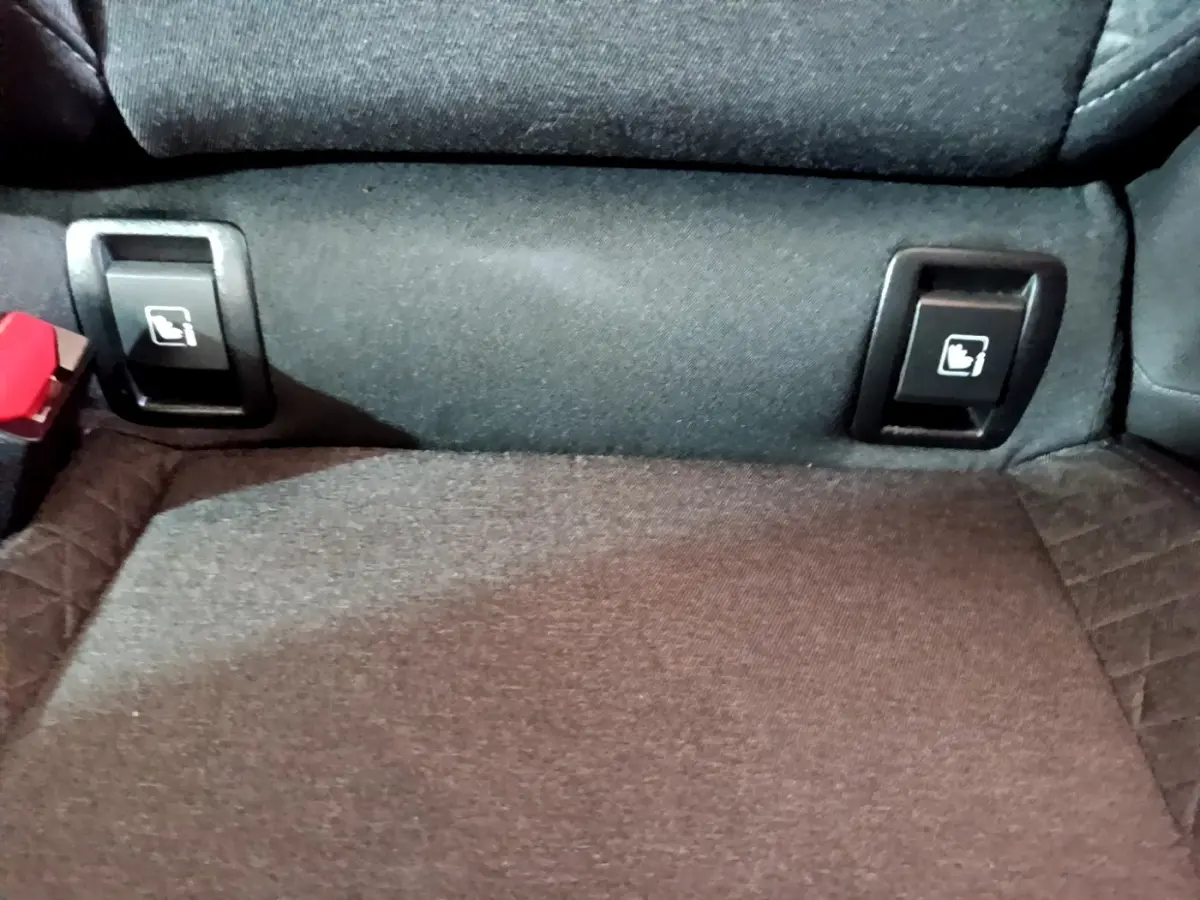 Détail des commandes de rabattement des sièges arrière sur la banquette tissu d'une Renault Clio Business blanche.