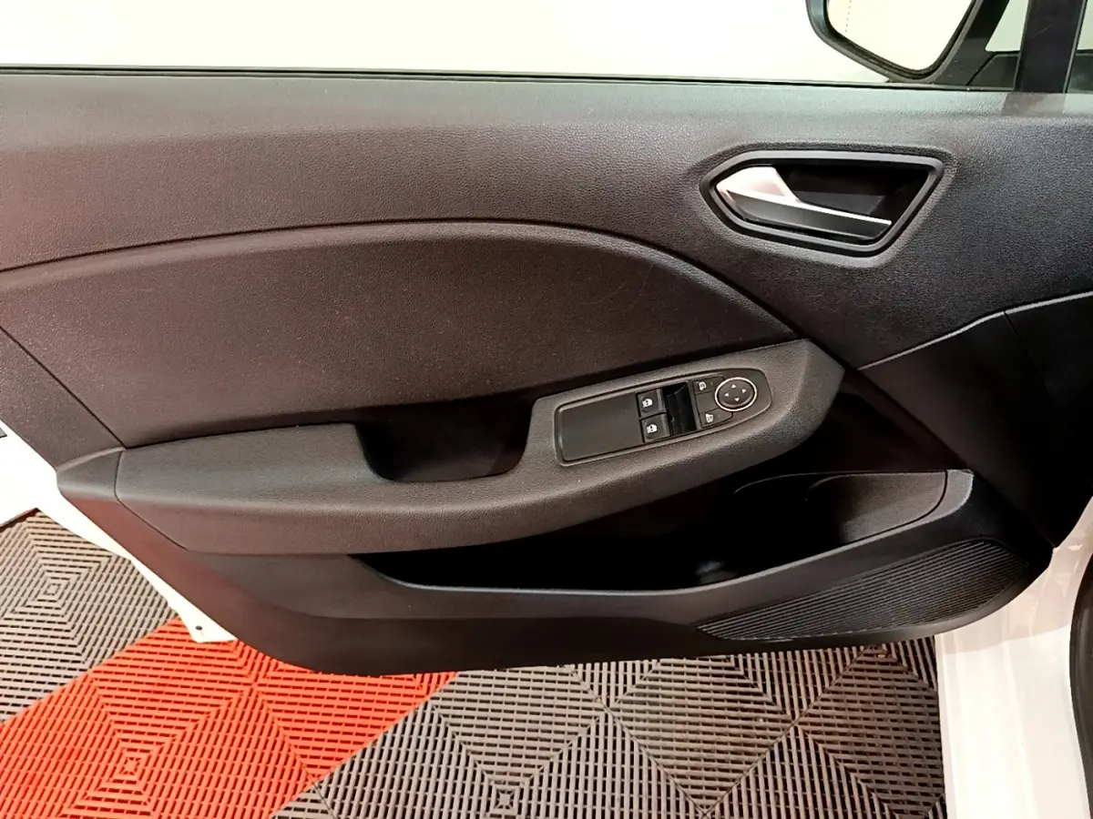 Vue rapprochée de la porte avant gauche noire d'une Renault Clio Business blanche, avec commandes de vitres électriques.