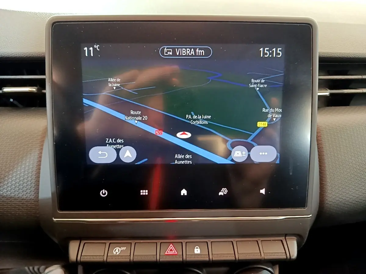 Écran tactile central affichant la navigation 3D dans l’habitacle d’une Renault Clio Business blanche, vue de face.