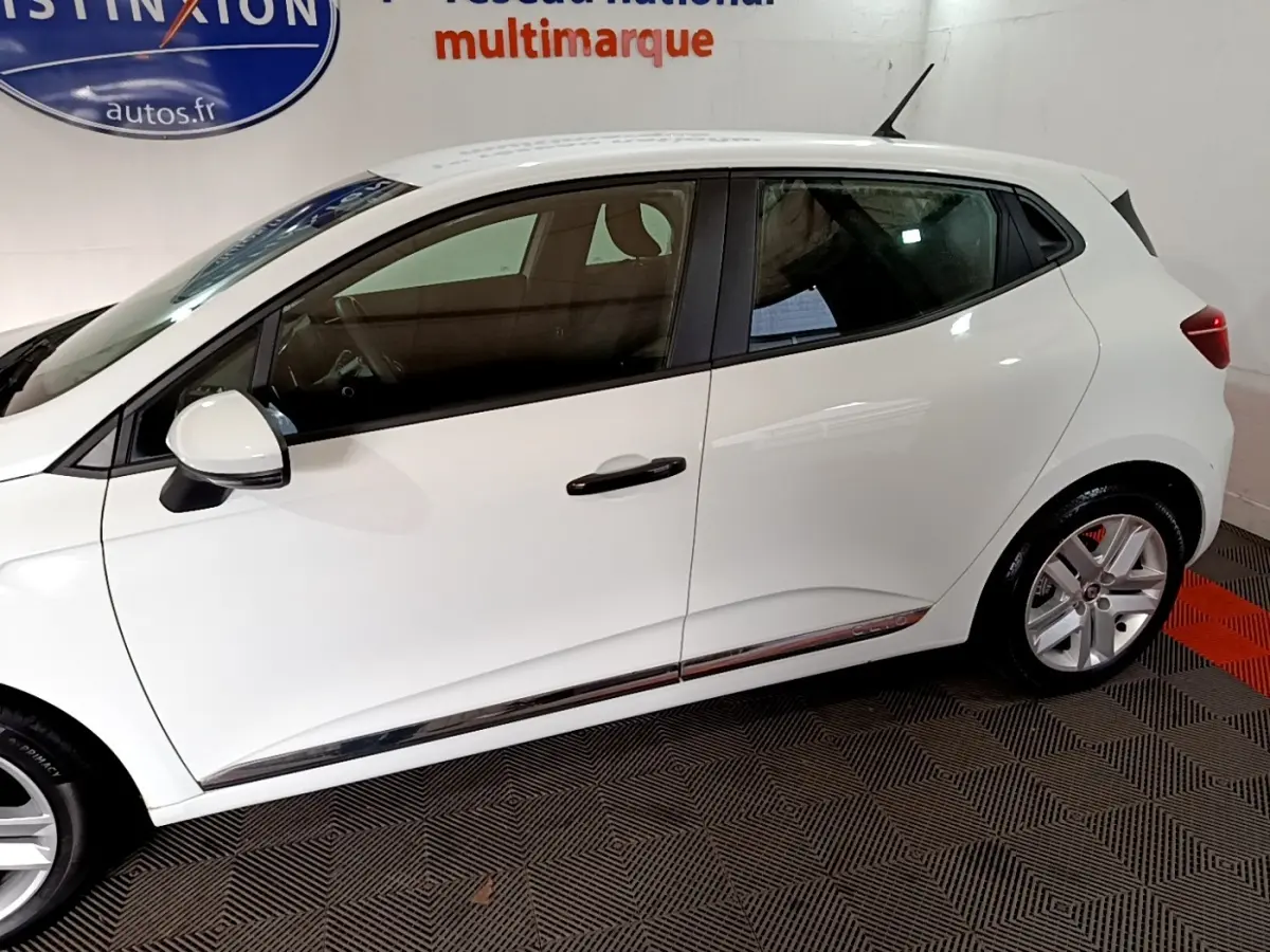 Profil côté gauche de la Renault Clio Business blanche 2021, avec jantes alliage et poignées de porte noires.