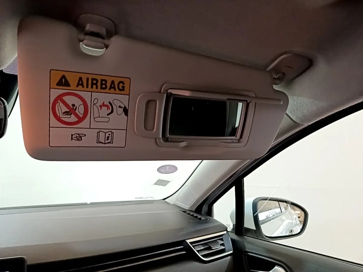 Intérieur de la Renault Clio Business blanc, vue côté passager avec pare-soleil et miroir ouvert.