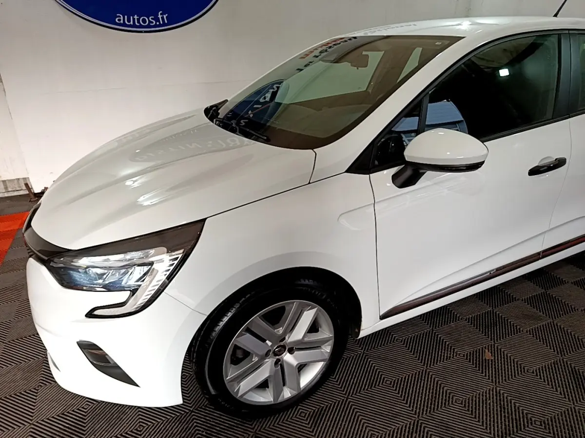 Vue 3/4 avant droit d'une Renault Clio Business blanche avec phares LED et jantes alliage argentées.