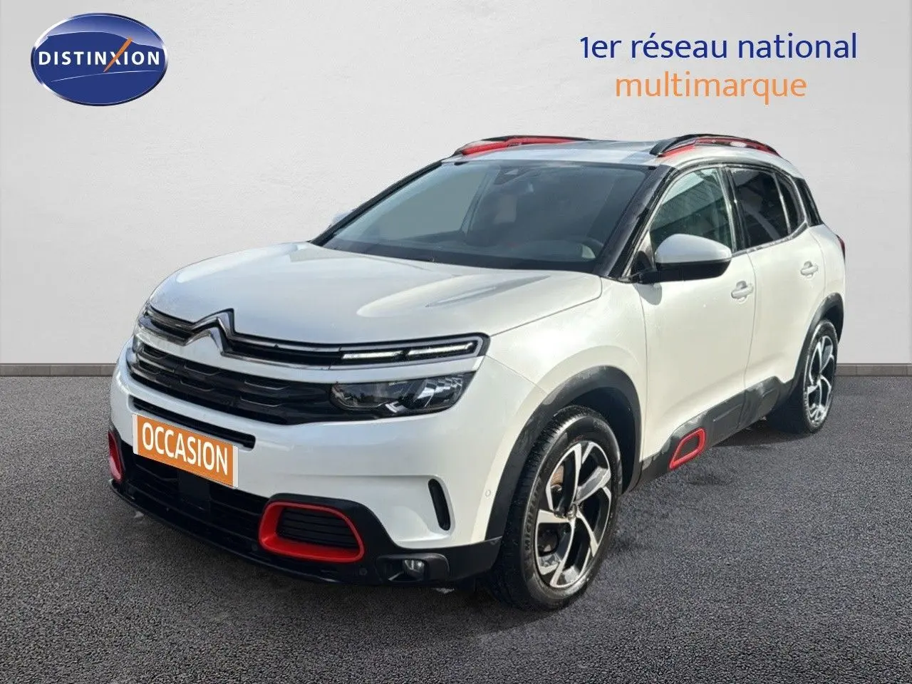 Citroën C5 Aircross blanc nacré, vue 3/4 avant droit avec détails rouges sur boucliers et jantes bicolores.