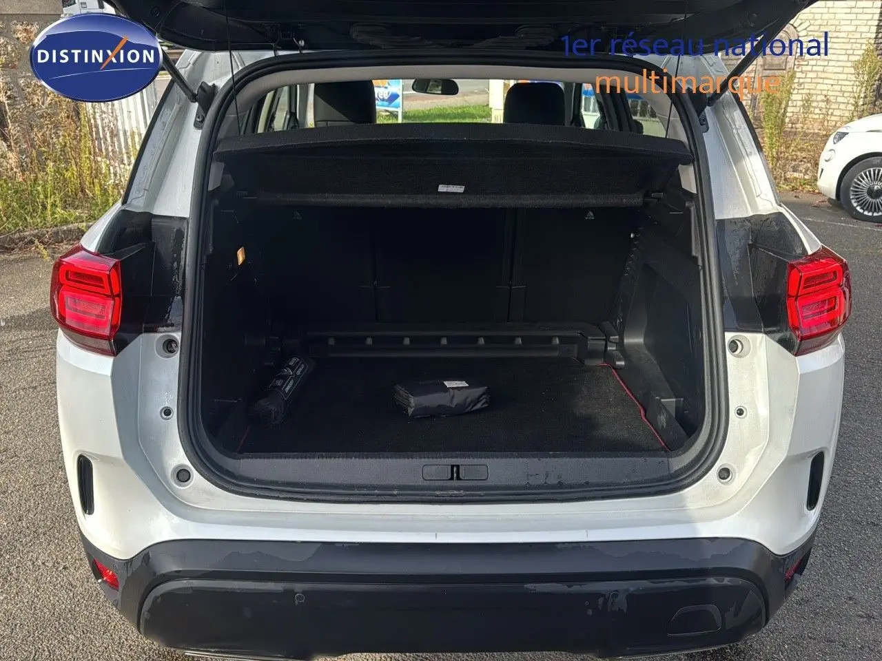 Vue arrière du Citroën C5 Aircross blanc nacré métal avec coffre ouvert montrant un intérieur spacieux et noir.