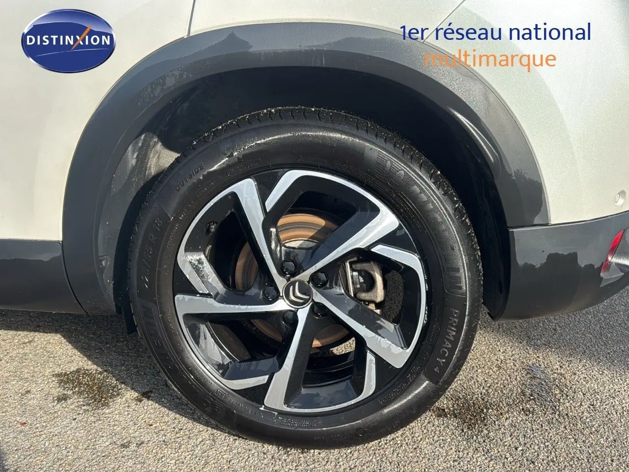 Gros plan sur la roue arrière droite d’un Citroën C5 Aircross blanc nacré avec jante alliage bicolore noire et argent.