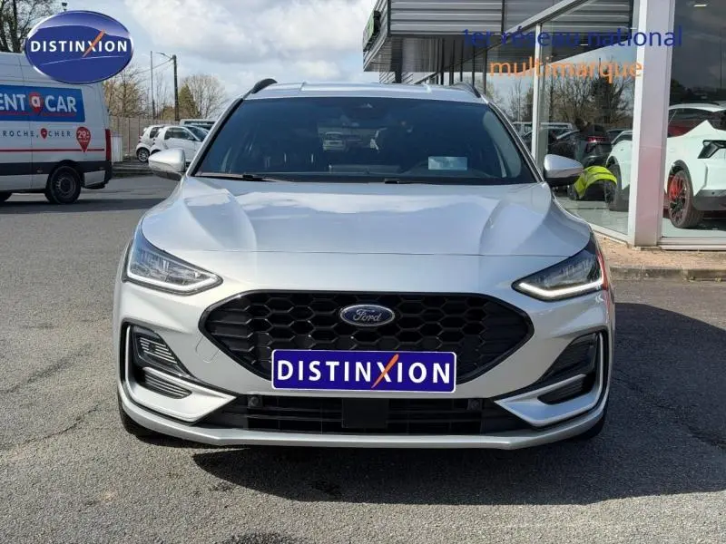 Vue frontale d'une Ford Focus SW 2023 gris lunaire métallisé avec calandre noire et phares LED allumés.