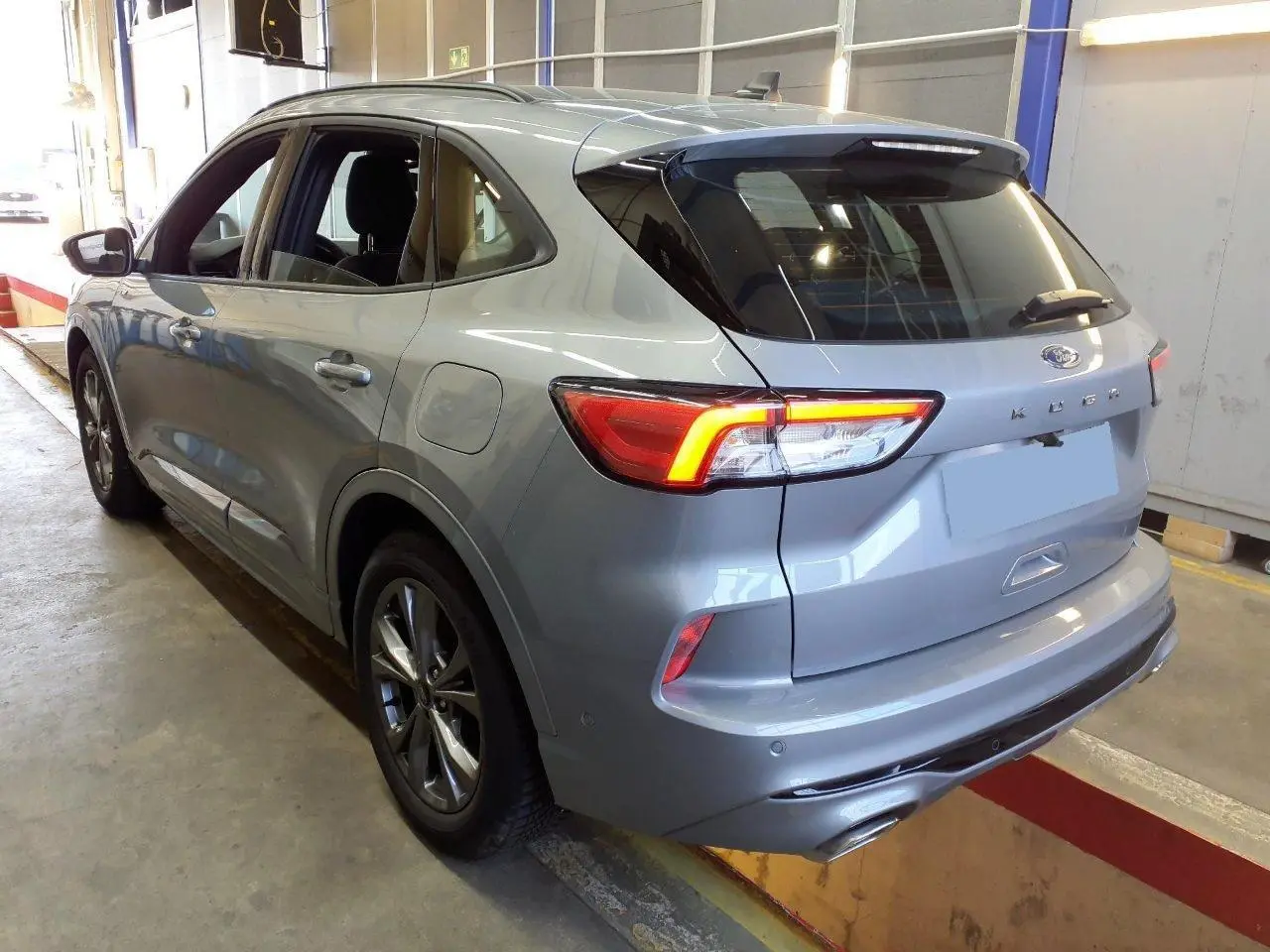 Vue 3/4 arrière droite du Ford Kuga gris Solar 2024 avec feux LED allumés et double sortie d'échappement ST-Line.