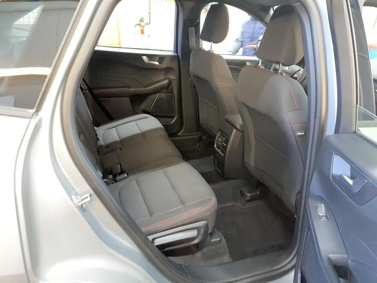 Vue intérieure côté droit des sièges arrière gris foncé avec surpiqûres rouges du Ford Kuga 2024 gris Solar.