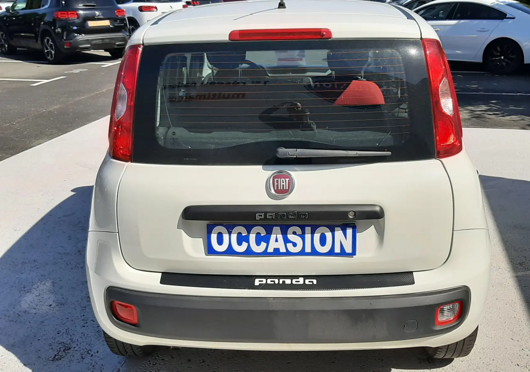Vue arrière d'une Fiat Panda blanche 2018 avec plaque "OCCASION" et feux arrière rouges visibles.
