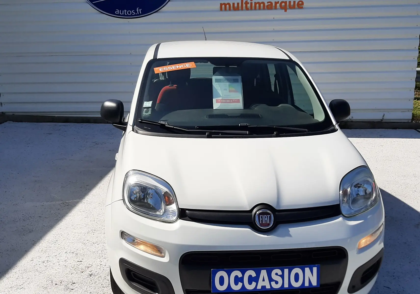 Vue avant d'une Fiat Panda blanche 2018 essence, avec plaque "OCCASION" et sticker orange "ESSENCE" sur le pare-brise.
