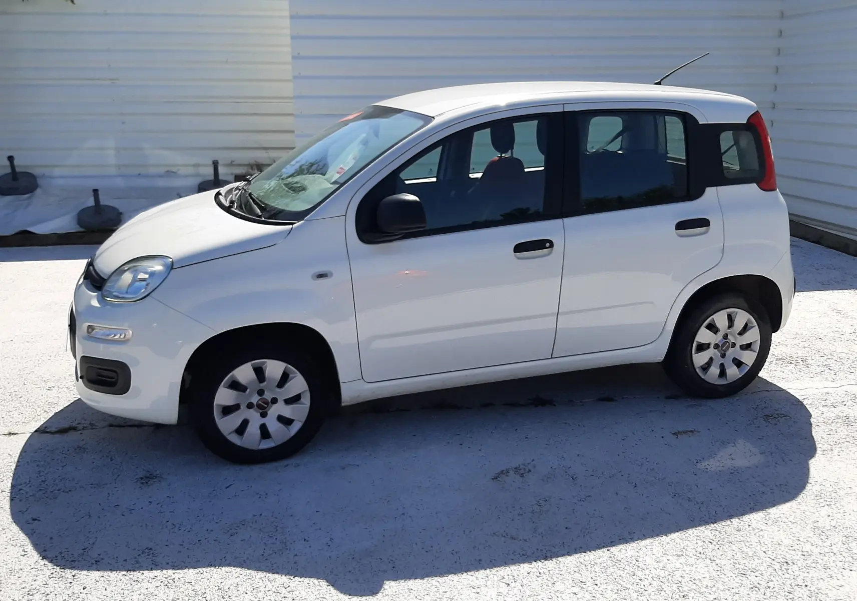 Profil côté gauche d'une FIAT Panda blanche 2018 à cinq portes, avec rétroviseurs noirs et jantes simples.