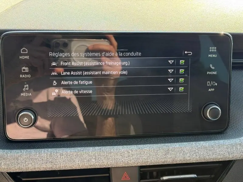 Écran tactile central de la Skoda Scala 2025 affichant les réglages des aides à la conduite, avec cadre noir et tableau de bord gris.