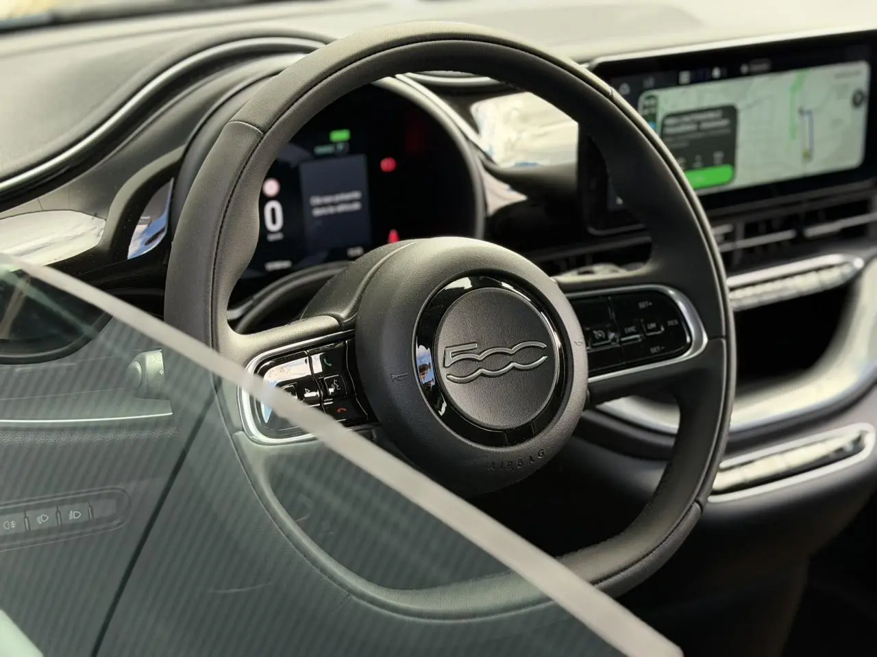 Vue rapprochée du volant noir Soft-Touch du Fiat 500 électrique 2024 avec tableau de bord numérique et écran tactile.