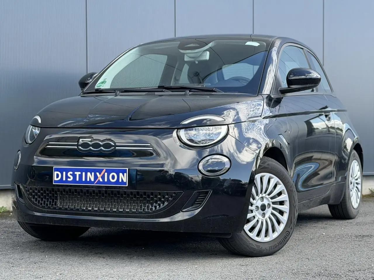Vue 3/4 avant droite d'une Fiat 500 électrique 2024 en noir Onyx avec jantes blanches et calandre lisse.
