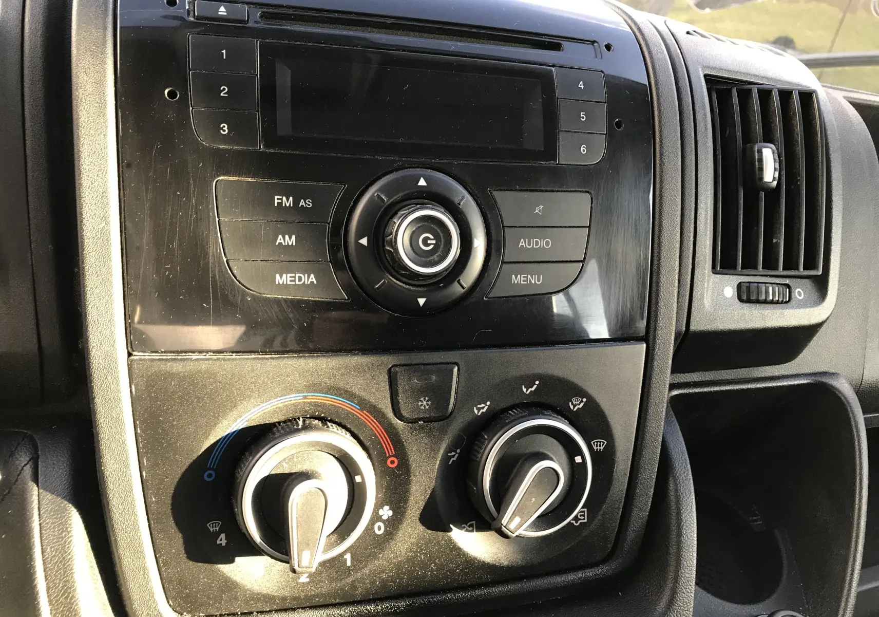 Tableau de bord intérieur du Peugeot Boxer 2014, vue rapprochée sur la console centrale avec commandes audio et climatisation.
