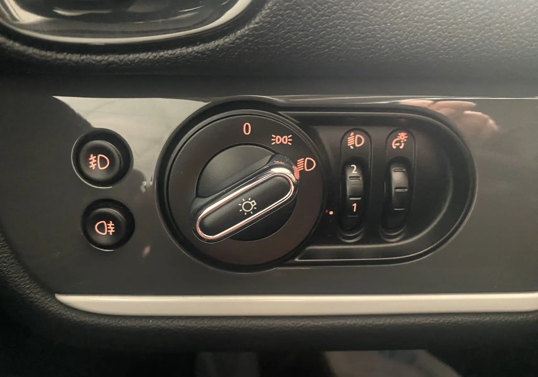 Gros plan sur les commandes d'éclairage du tableau de bord d'une MINI Countryman rouge toit noir de 2018.