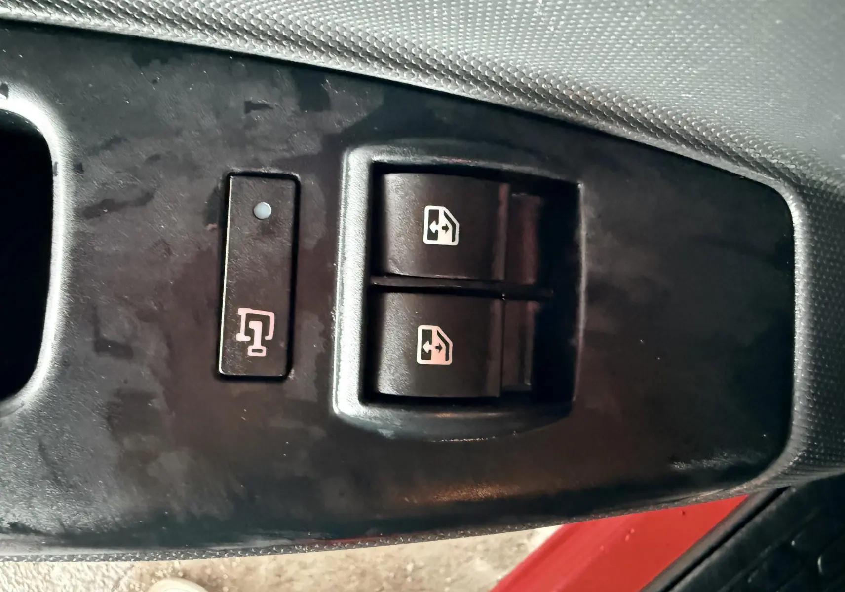 Gros plan sur les commandes de lève-vitres électriques côté conducteur du Fiat Doblo Cargo rouge de 2011.