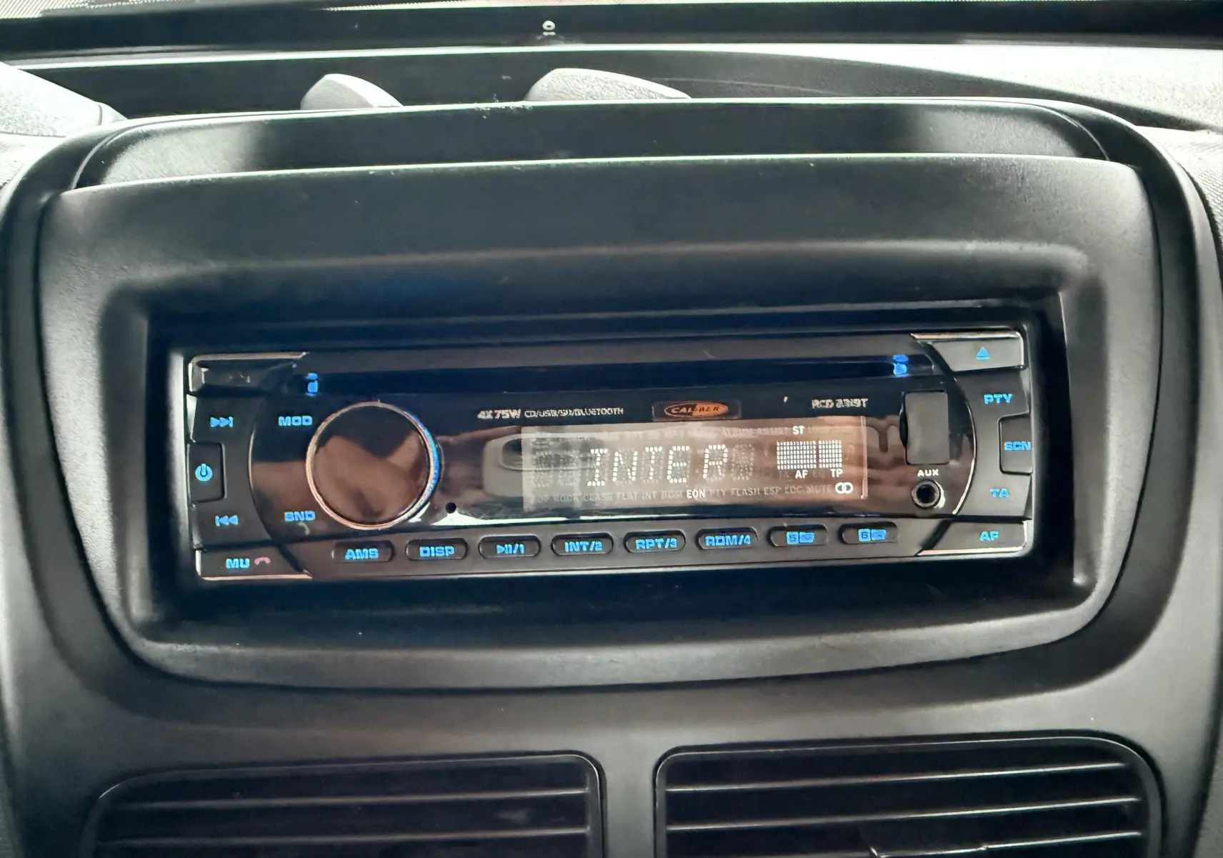 Gros plan sur la radio noire intégrée au tableau de bord du Fiat Doblo Cargo rouge de 2011.