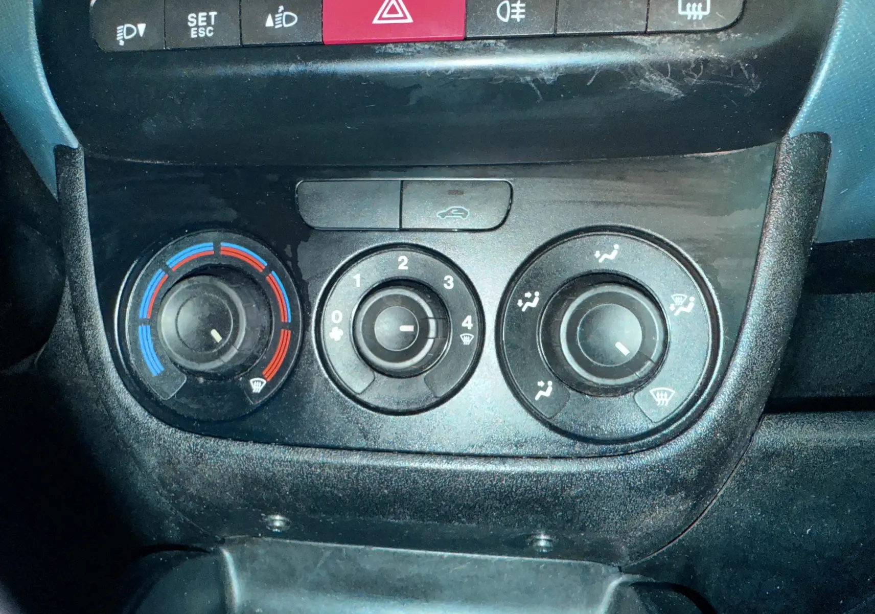 Gros plan sur les commandes de climatisation et boutons de sécurité du tableau de bord du Fiat Doblo Cargo 2011.