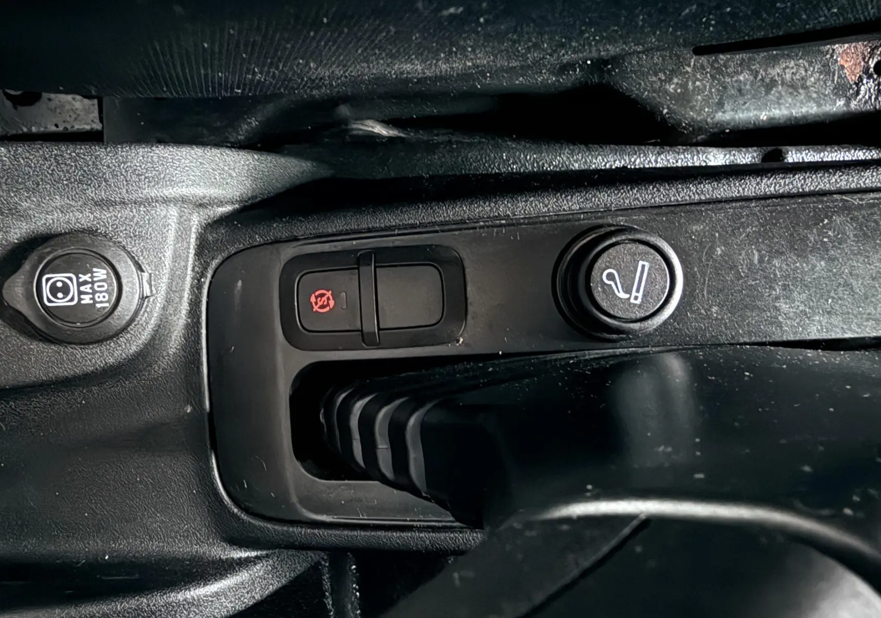 Gros plan sur la console centrale noire du Fiat Doblo Cargo 2011 montrant les boutons de commande et prise 12V.