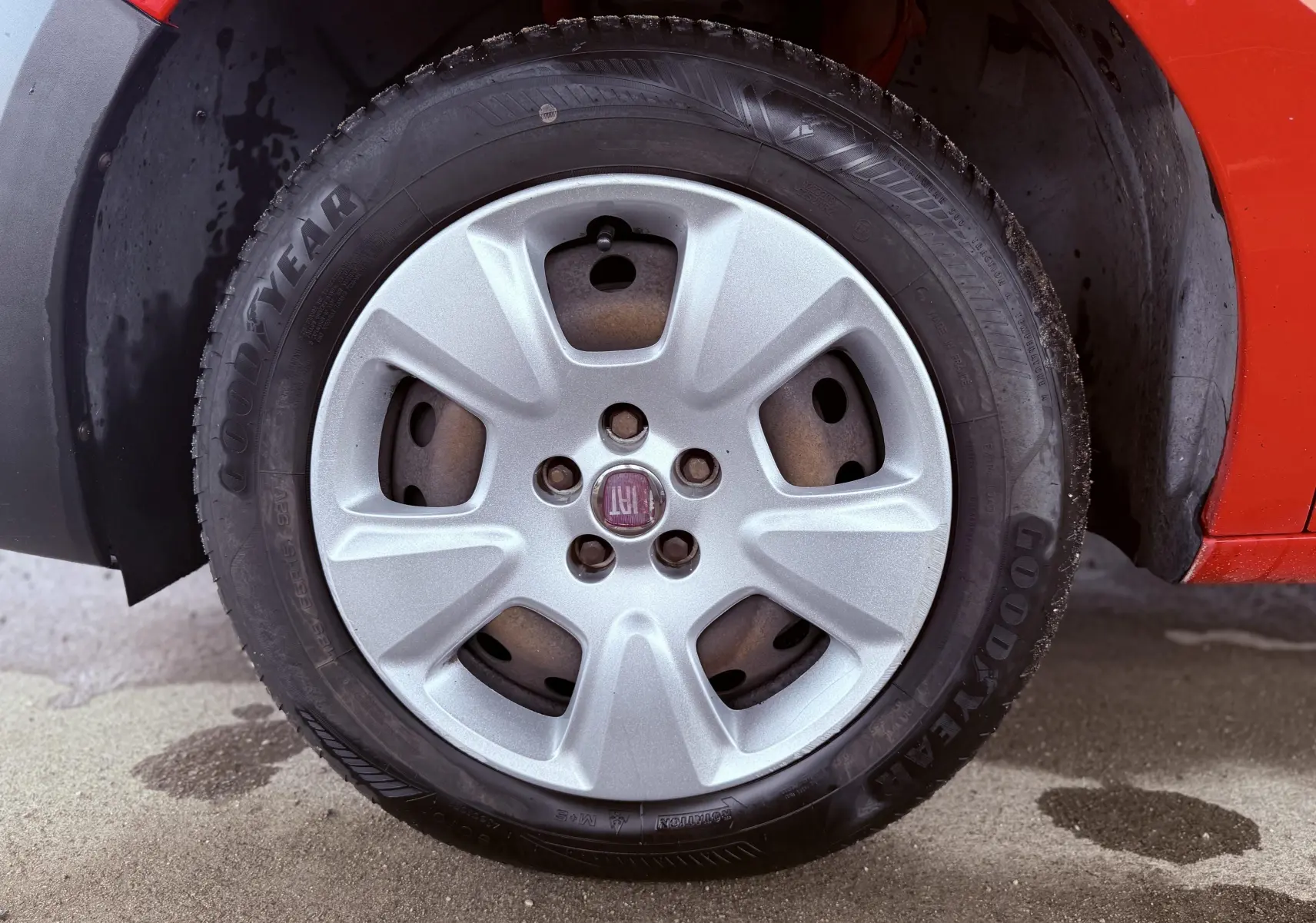Gros plan sur la roue avant droite d’un FIAT Doblo Cargo rouge, avec jante en alliage argentée et pneu Goodyear.