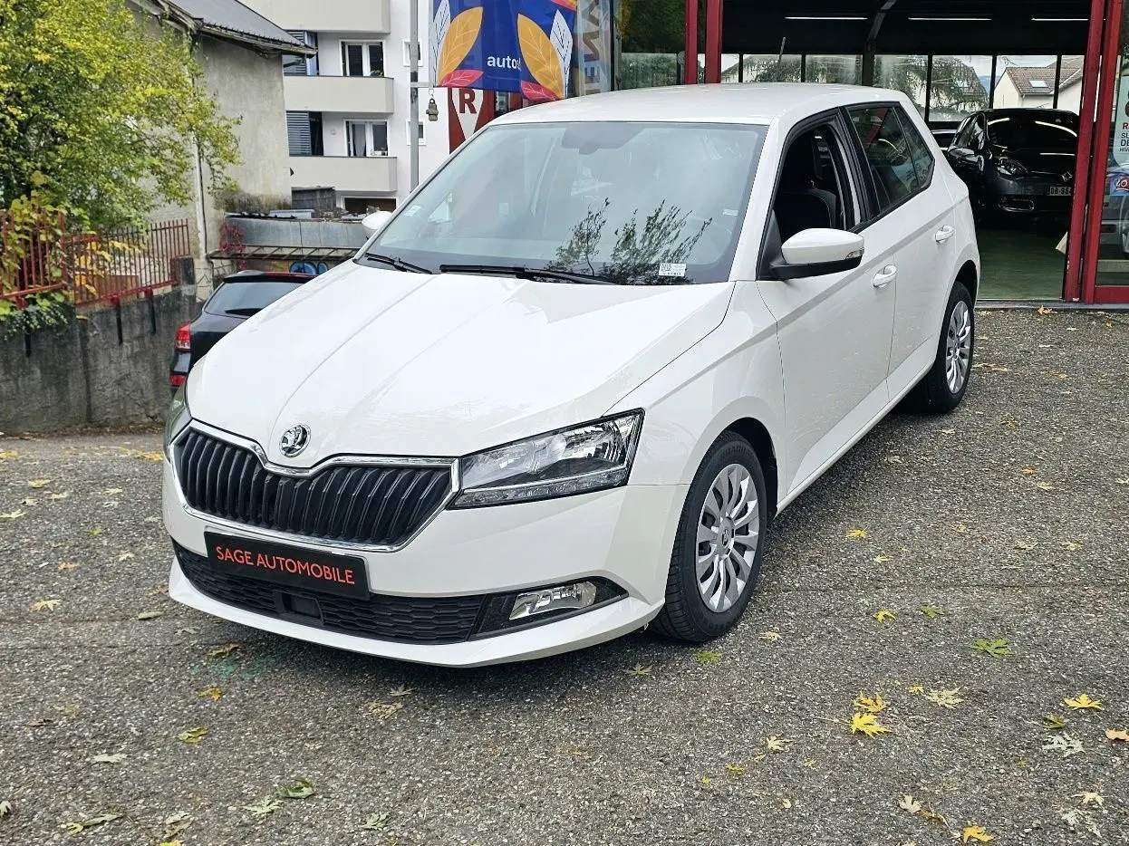 Vue 3/4 avant droite d'une Skoda Fabia blanche Cristal avec calandre noire et enjoliveurs 15 pouces visibles.