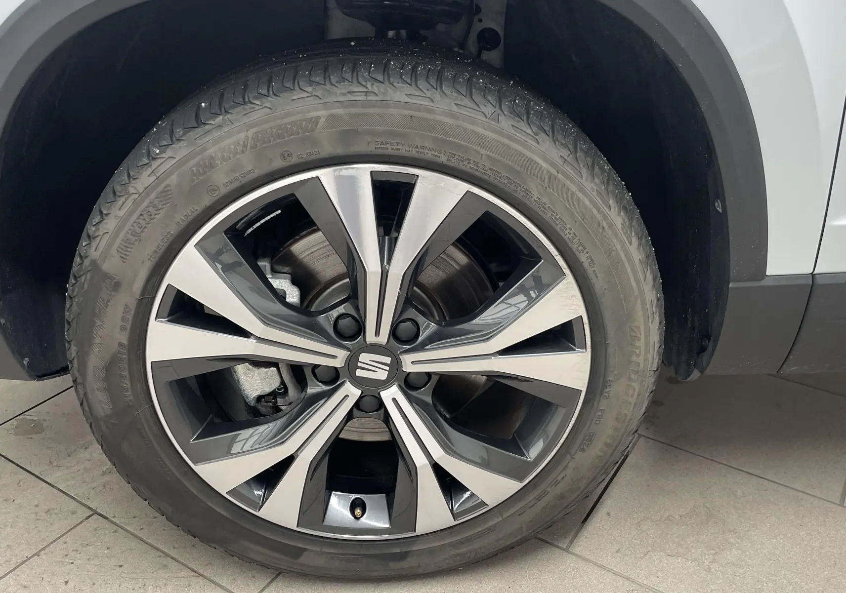 Gros plan sur la jante alliage 18'' usinée du côté avant droit d'un SEAT Ateca blanc Nevada 2024.