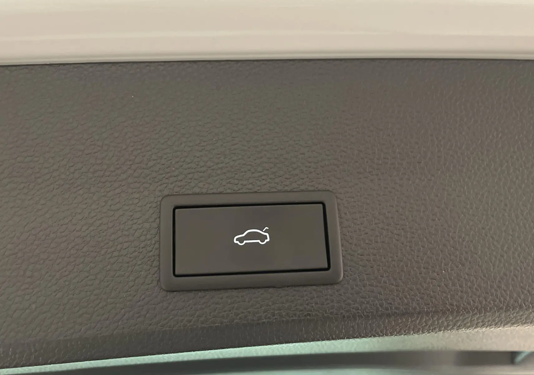 Bouton d'ouverture électrique du hayon sur un SEAT Ateca blanc Nevada, vue intérieure du coffre arrière.