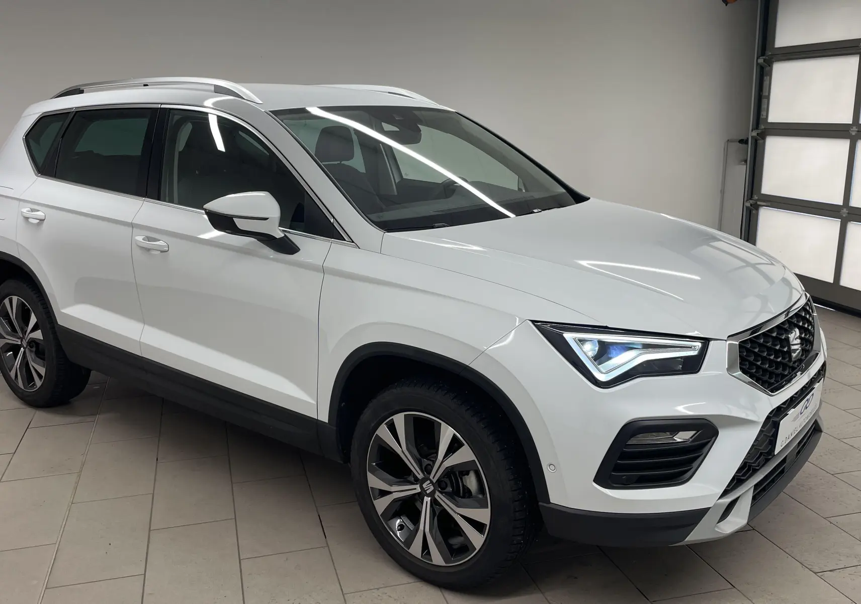 SEAT Ateca blanc Nevada en 3/4 avant droit, avec jantes alliage 18'' et hayon électrique mains libres.