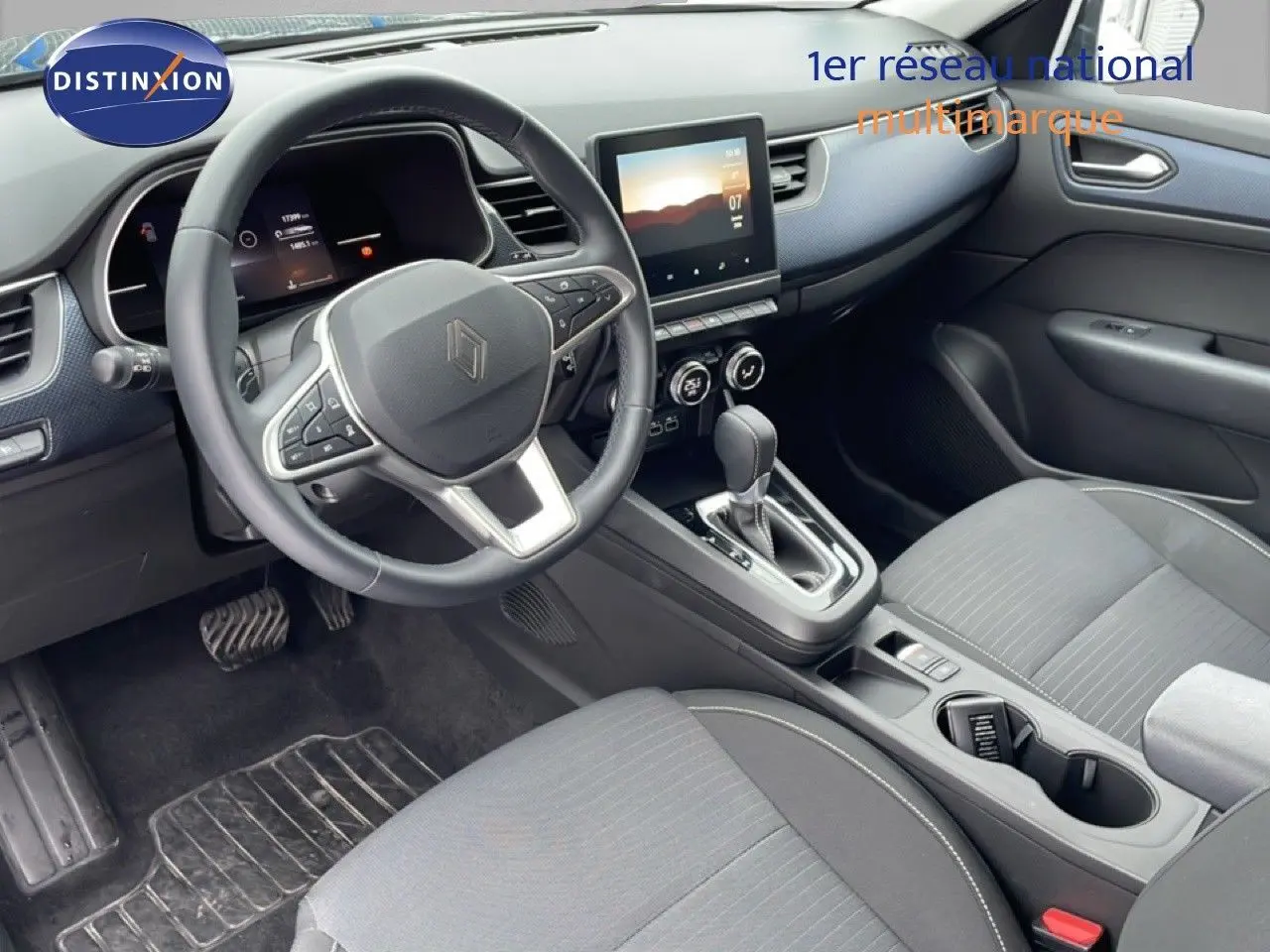 Vue intérieure côté conducteur du Renault Arkana 2025, avec tableau de bord moderne et sellerie tissu gris.