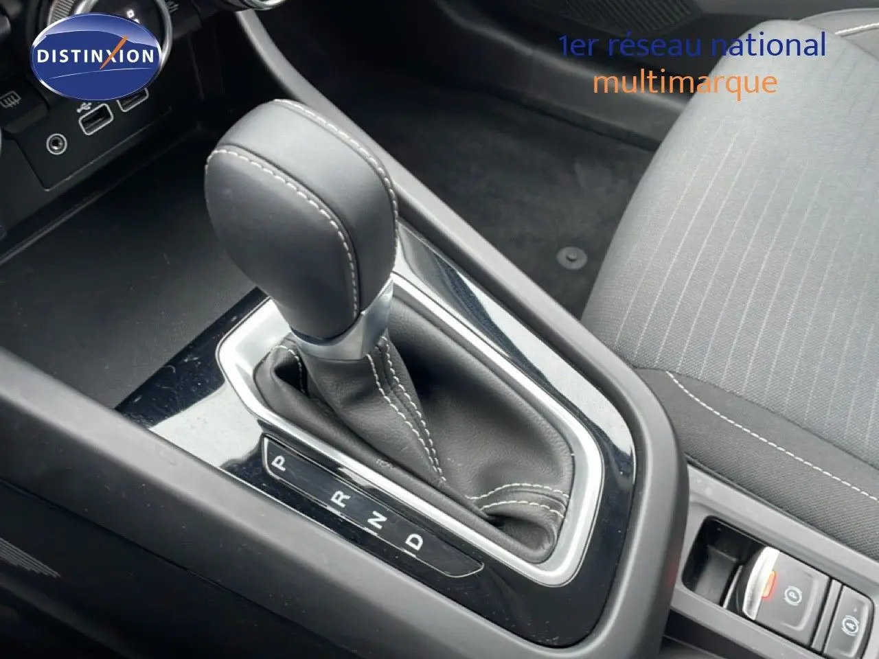 Gros plan sur la commande de boîte automatique et la sellerie tissu gris à coutures blanches dans un Renault Arkana 2025.