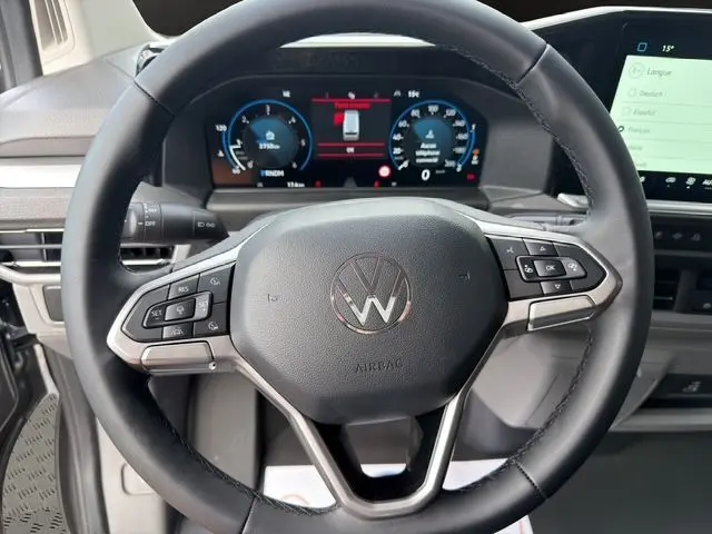 Vue rapprochée du volant multifonction noir du Volkswagen Transporter ProCab 2026 avec tableau de bord numérique et écran tactile.