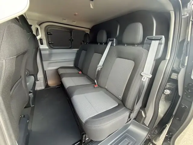 Vue intérieure côté droit du Volkswagen Transporter ProCab gris, montrant la banquette arrière 3 places en tissu rayé avec ceintures de sécurité.