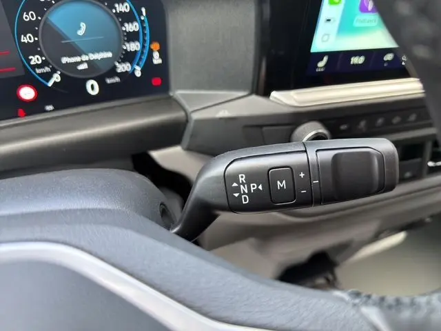 Gros plan sur la commande de boîte automatique DSG du Volkswagen Transporter ProCab gris, avec tableau de bord numérique en arrière-plan.